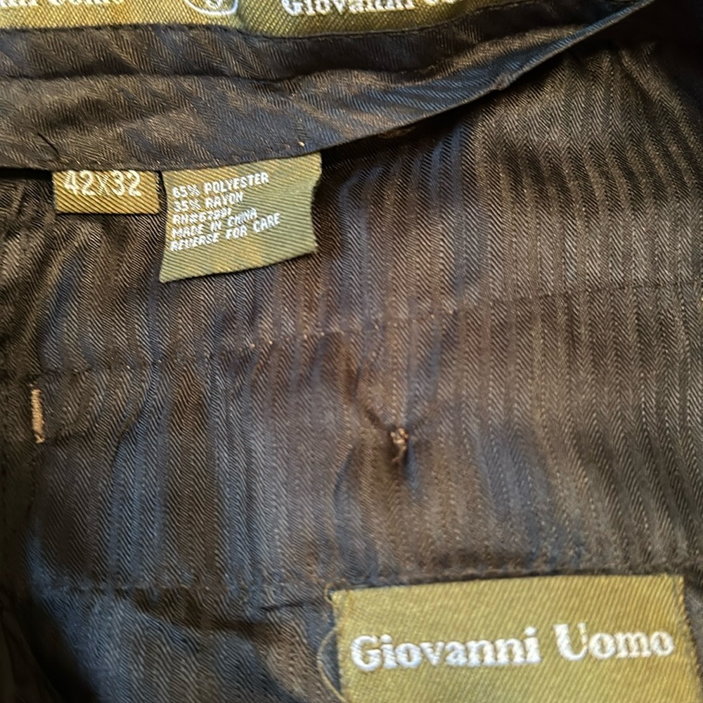 Dark brown pleated men’s pants with an adjustable waist.